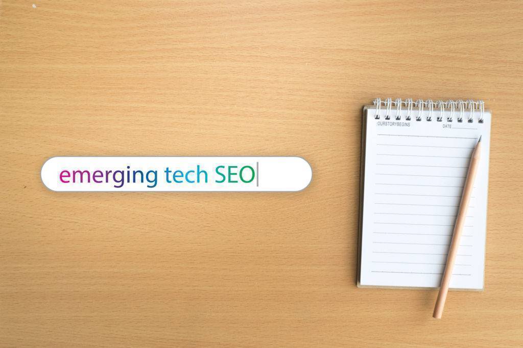 A notebook sitting on a desk next to search bar that says "emerging tech SEO"