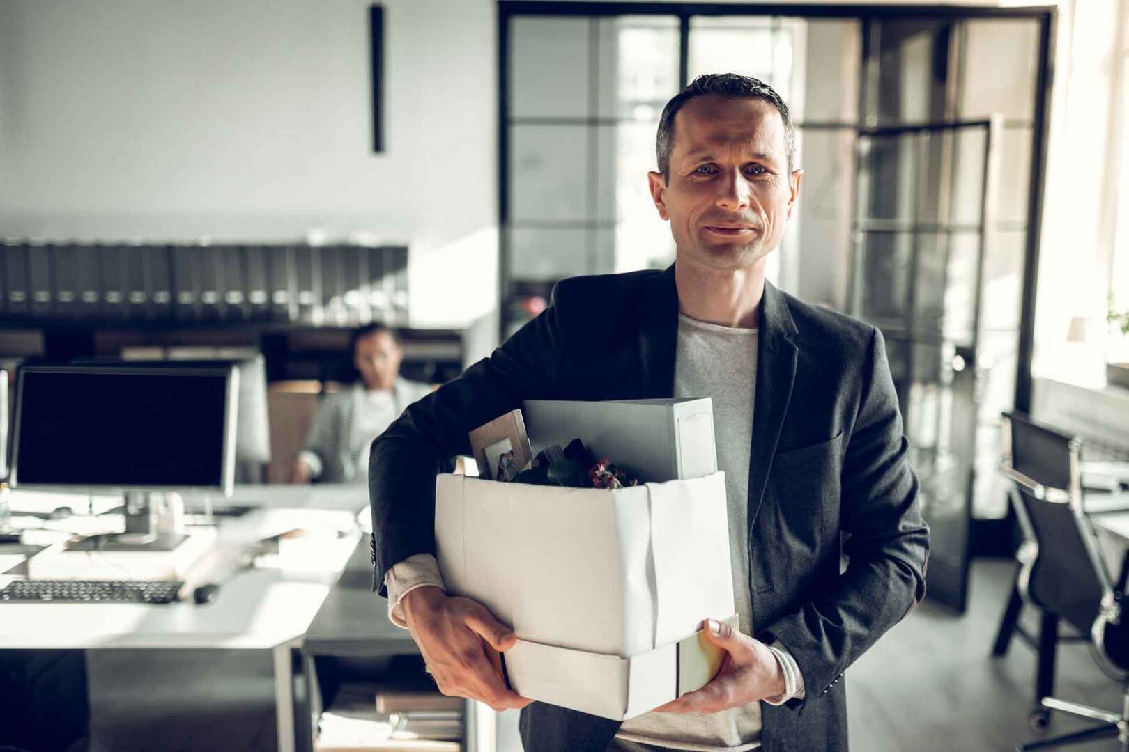 man leaving the office with a box of his belongings